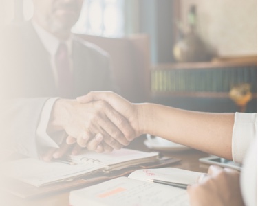 A handshake between business individuals at a meeting, illustrating teamwork and dedication to asbestos-exposure victims.